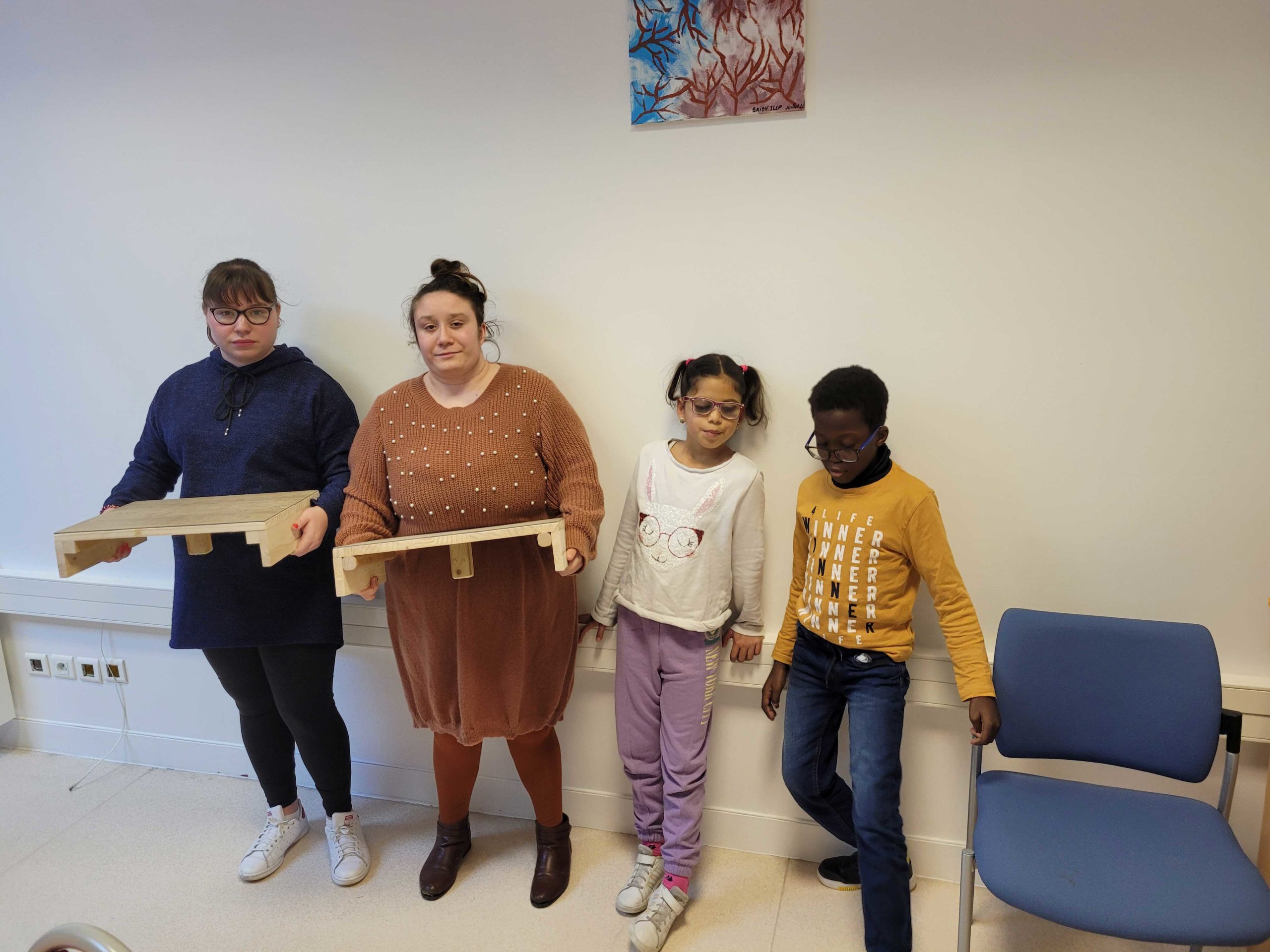 2 jeunes de l'EMP tiennent les repose-pieds à côté de 2 jeunes du SAIDV