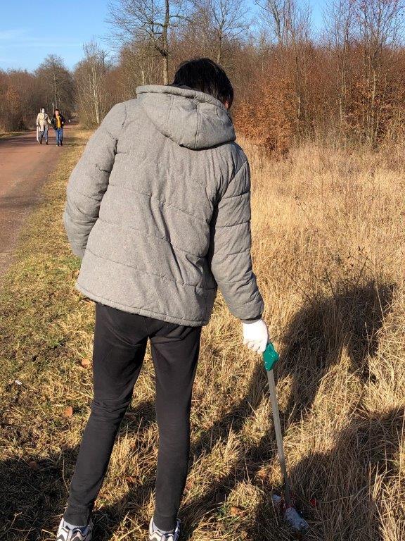 Un jeune ramasse un déchet avec une pince