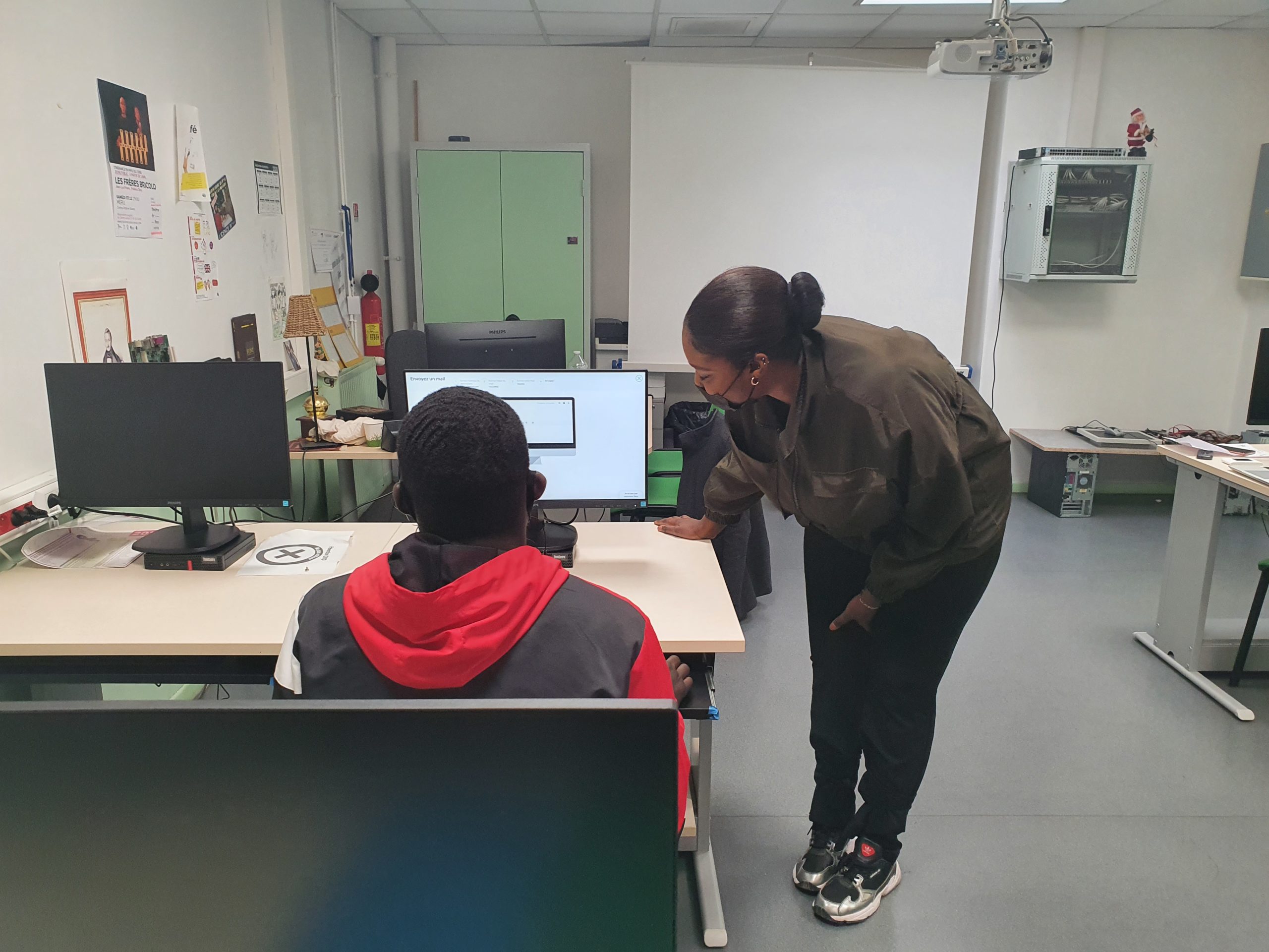 Une éducatrice explique à un jeune l'utilisation d'un ordinateur