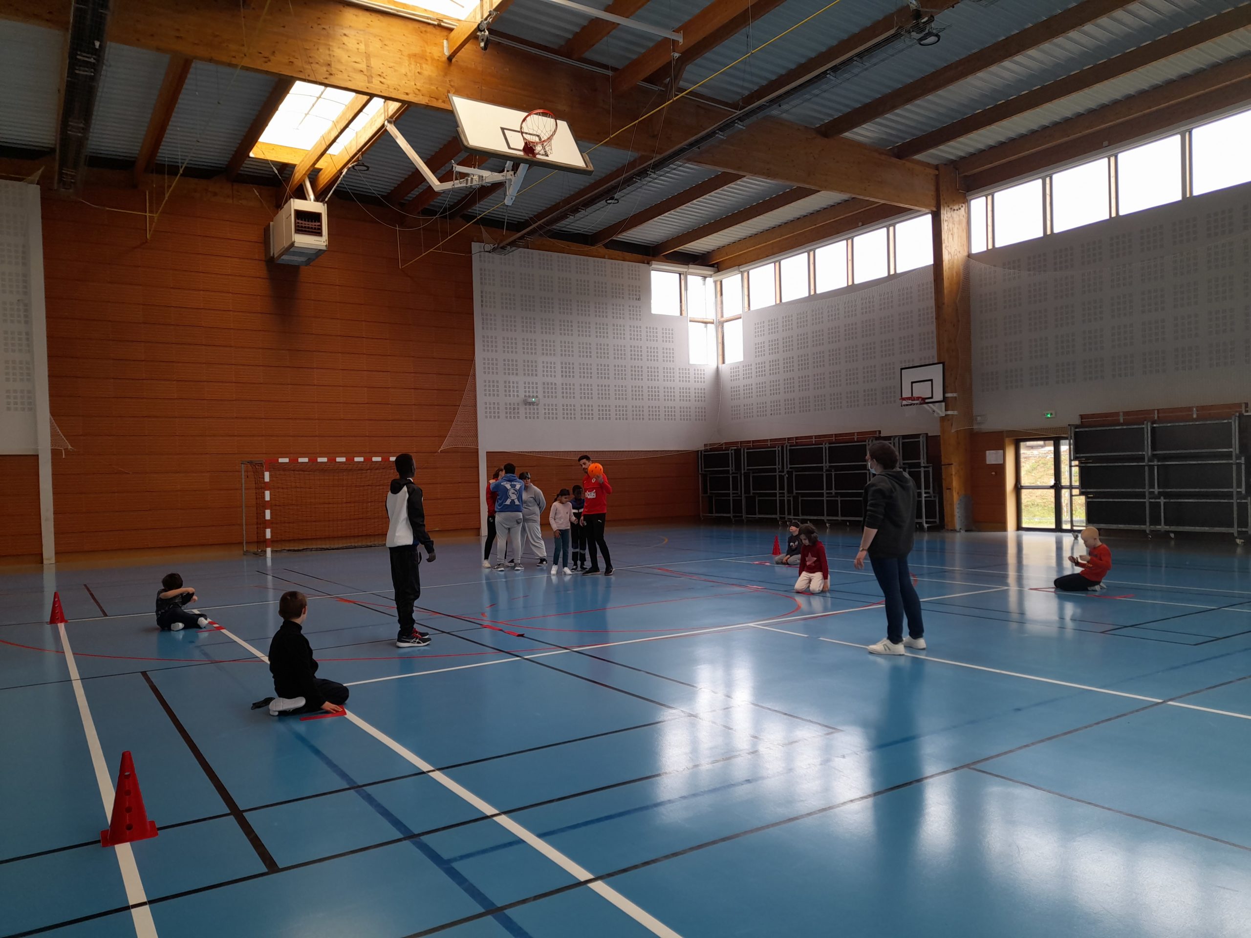 Des jeunes dans un gymnsae écoutent l'éducateur