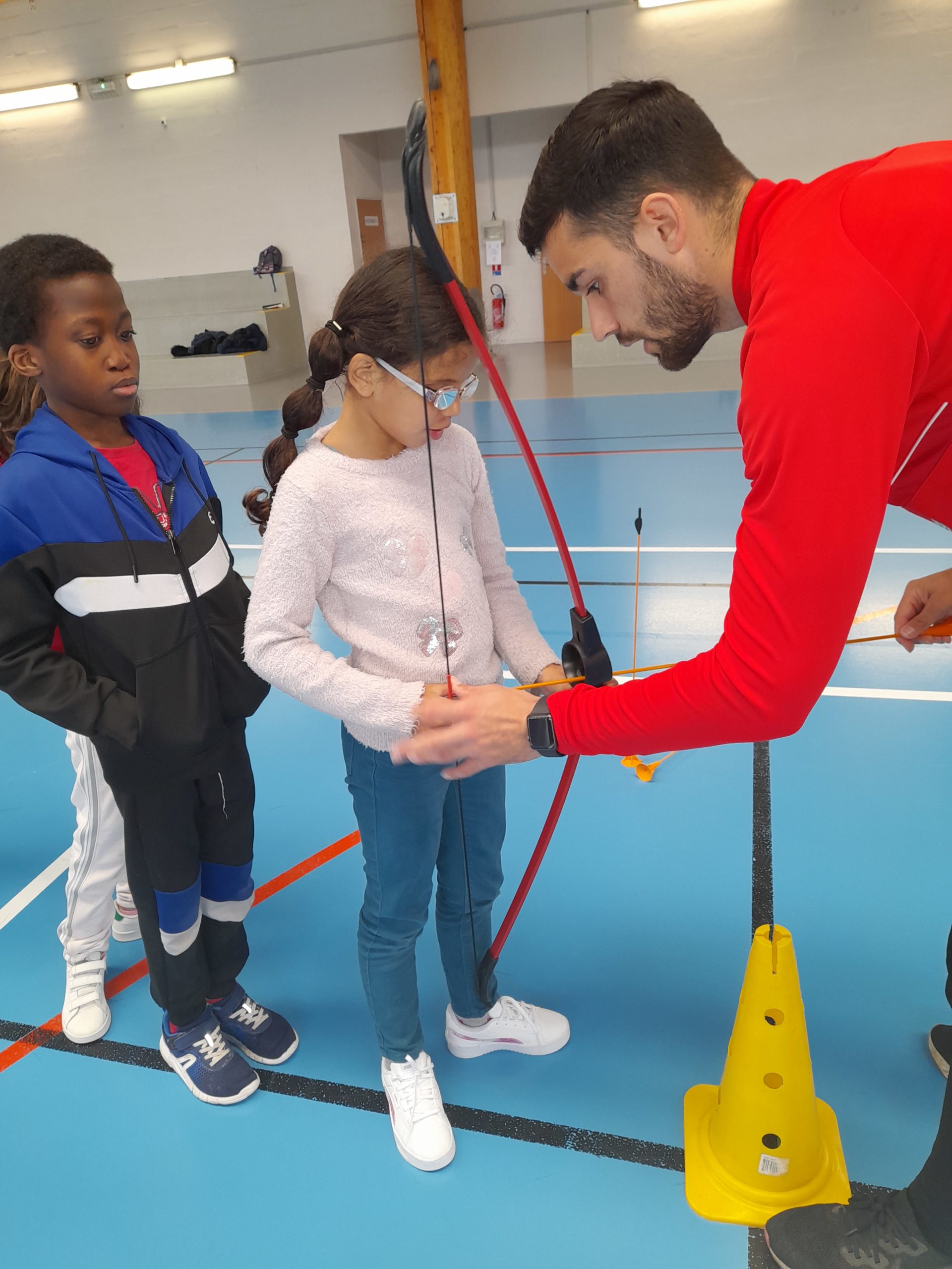 Un éducateur explique à une petite fille comment tenir son arc