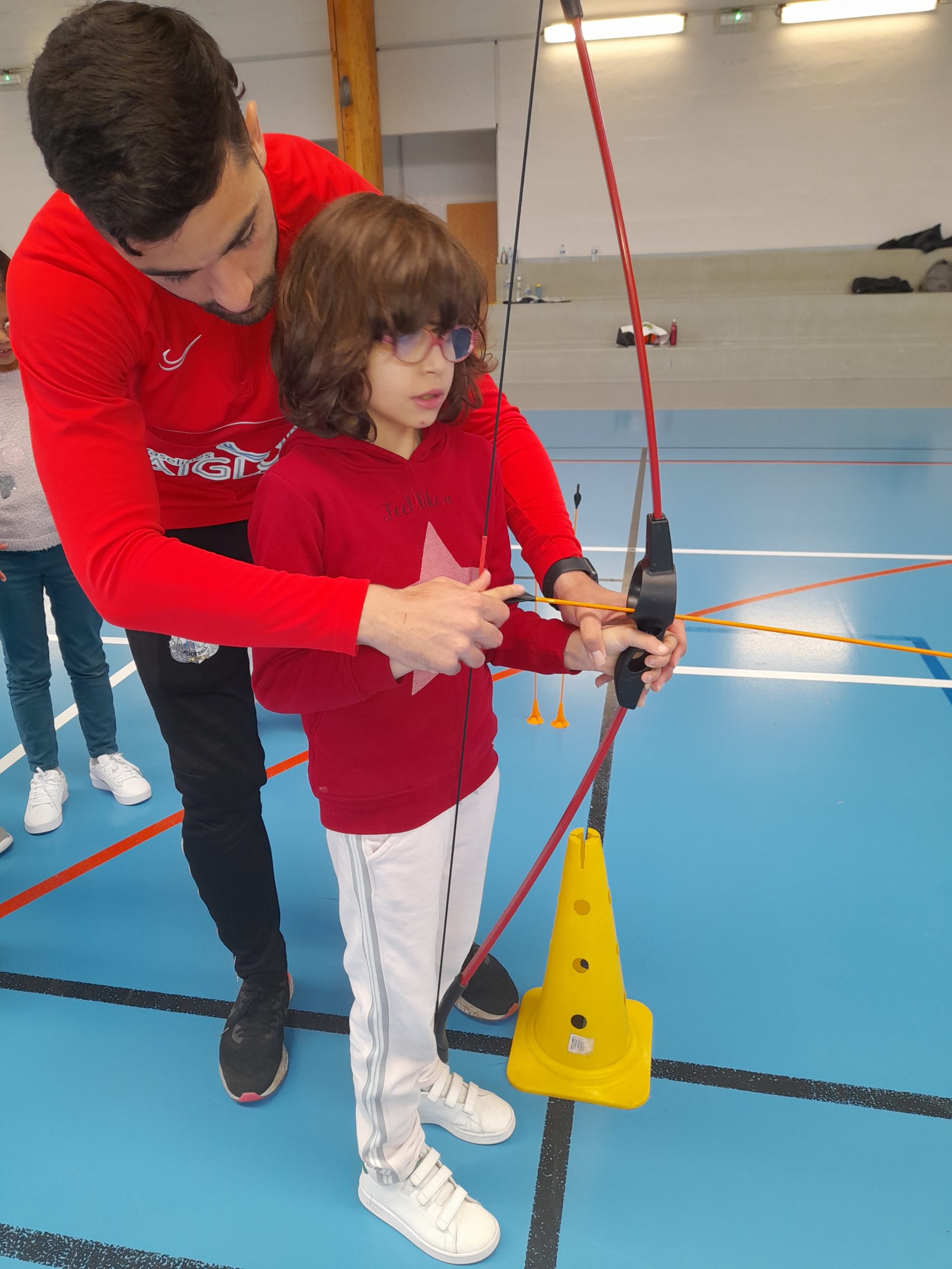 Un éducateur explique à une petite fille comment tenir son arc
