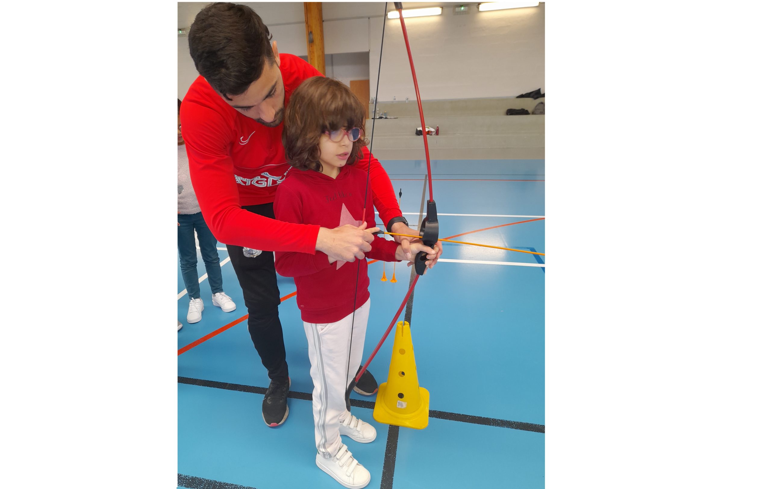 Un éducateur explique à une petite fille comment tenir son arc