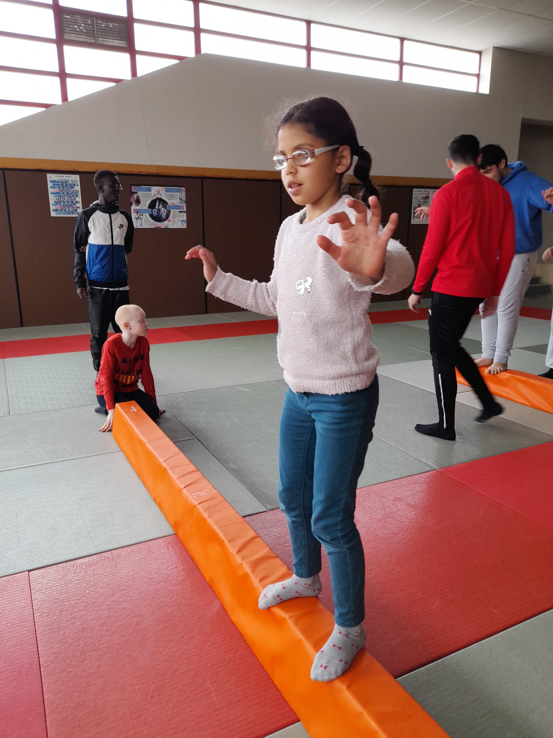 Une petite fille tient en équilibre sur une barre au sol