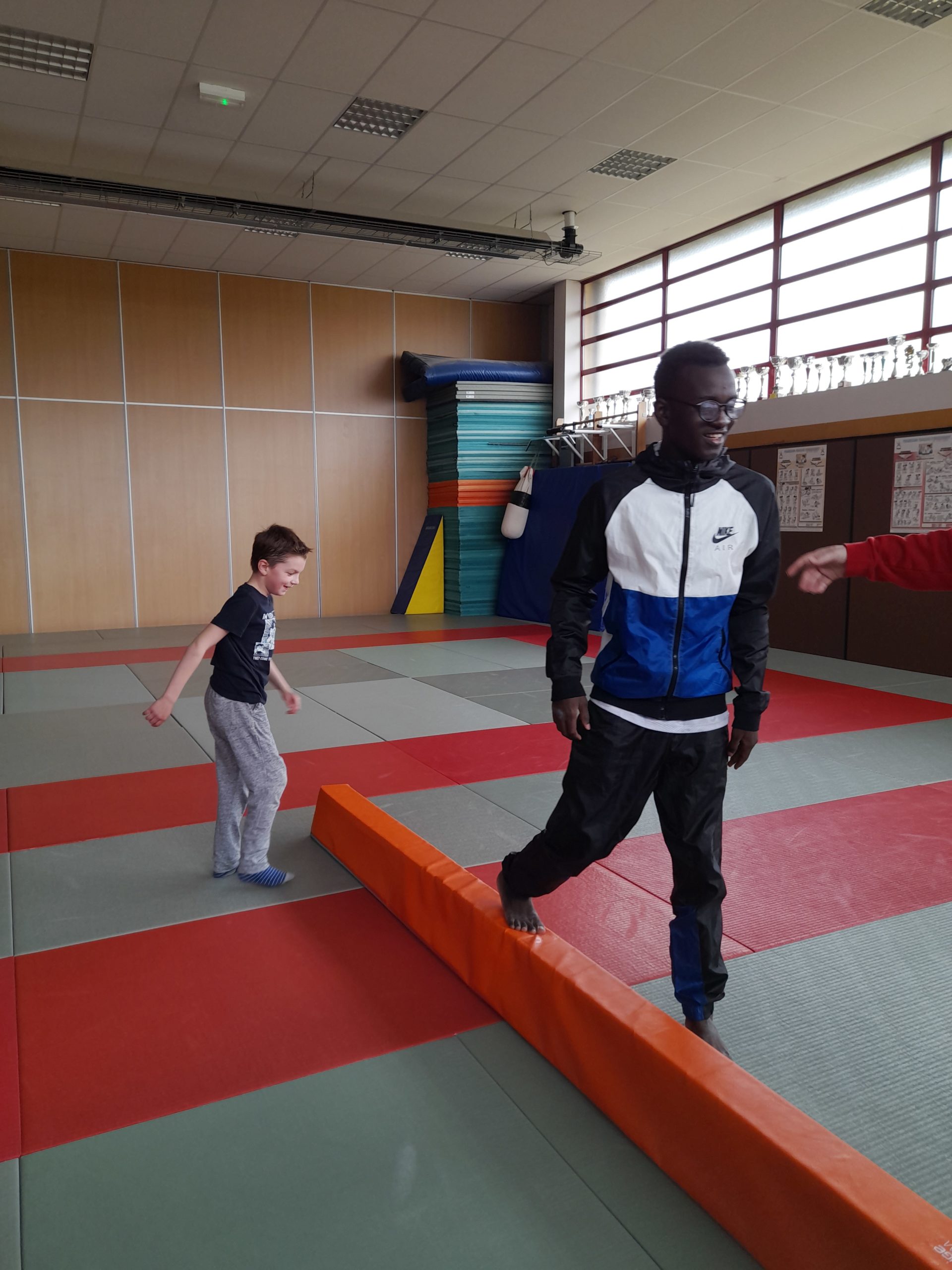 Des garçons s'entrainent à marcher sur une barre au sol