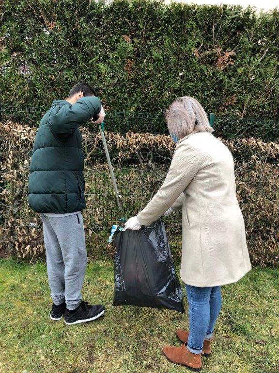 Un jeune dépose un déchet dans un sac avec une pince