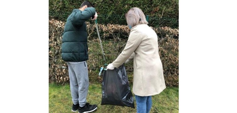 Un jeune dépose un déchet dans un sac avec une pince