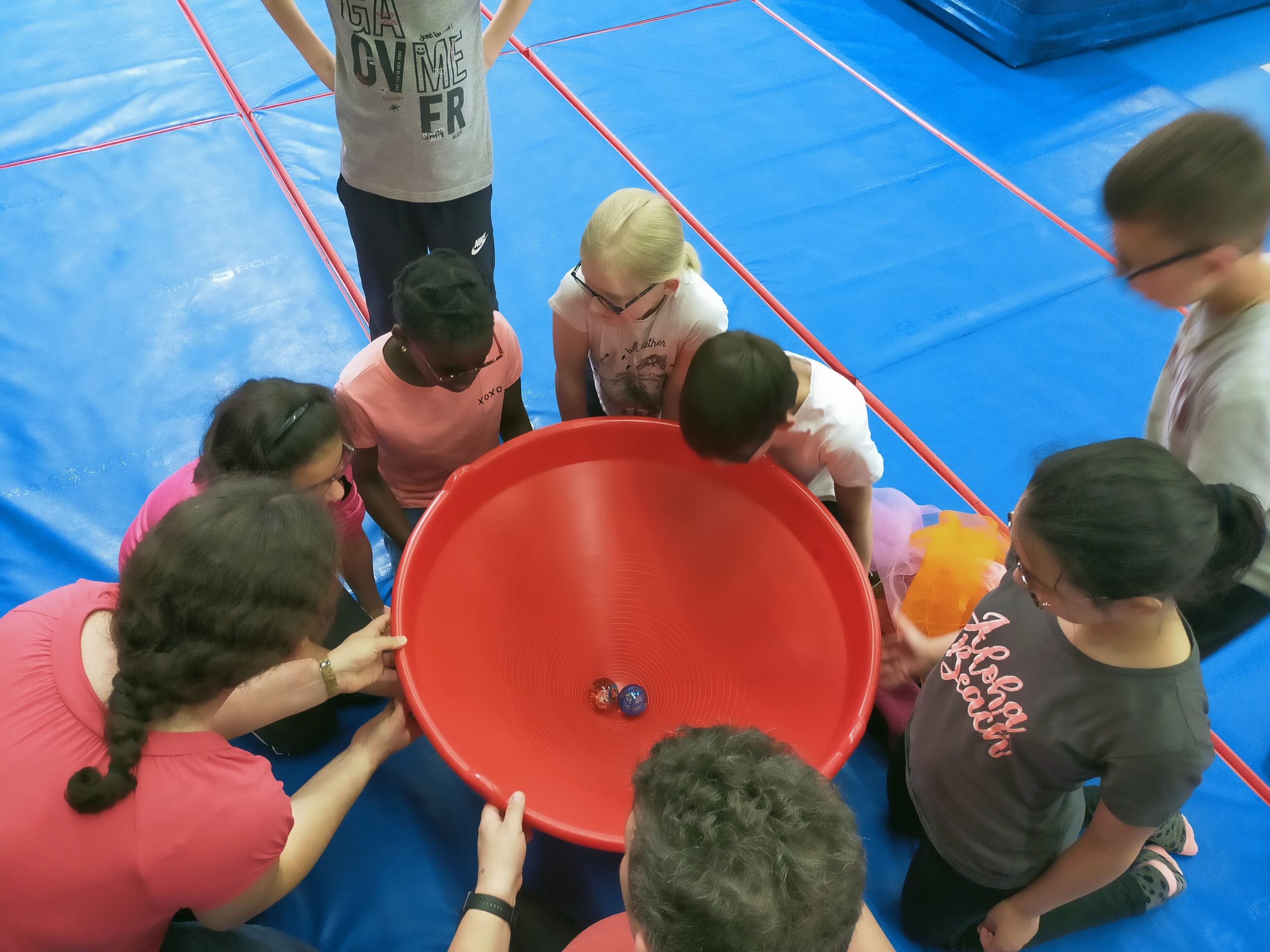 Des jeunes regardent 2 balles dans un grand récipient